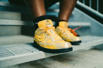 person wearing yellow and black nike athletic shoes
