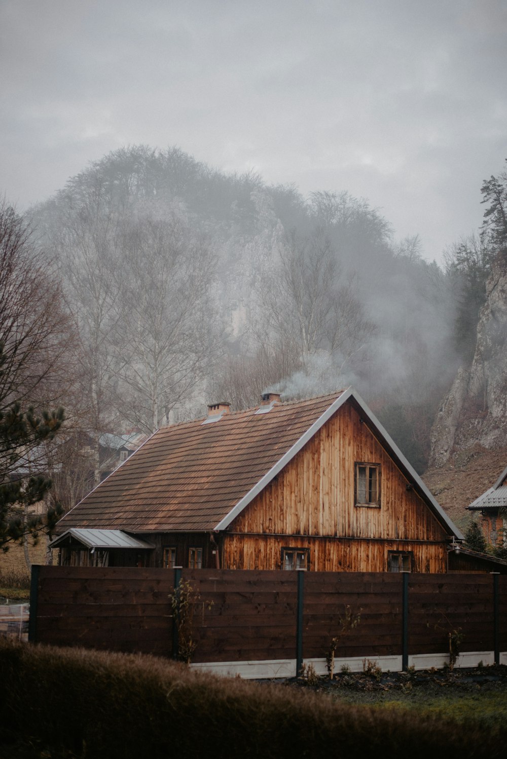 brown wooden house near trees under white clouds