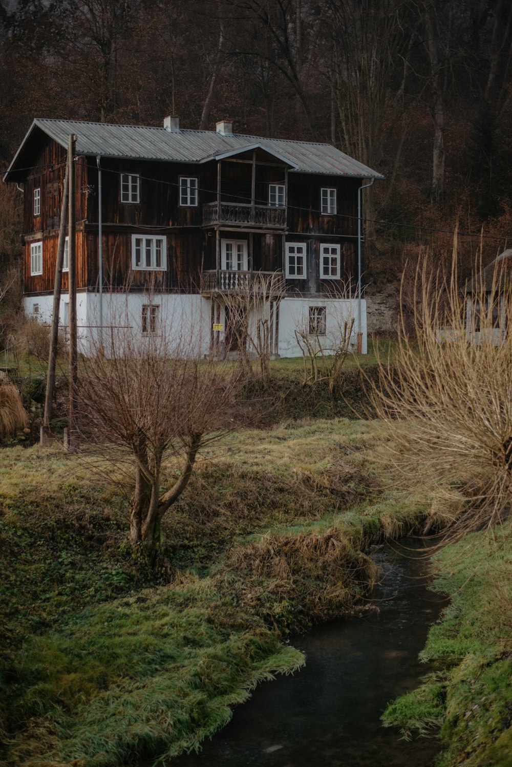 brown and white wooden house near green grass and body of water during daytime