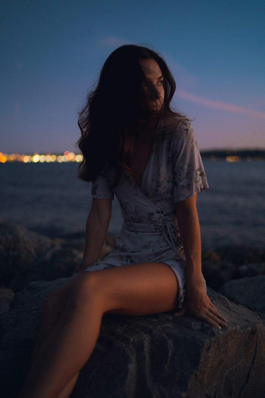 woman in gray shirt sitting on rock near body of water during daytime