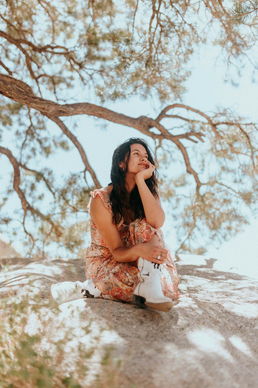 woman in white and brown floral dress sitting on white sand during daytime