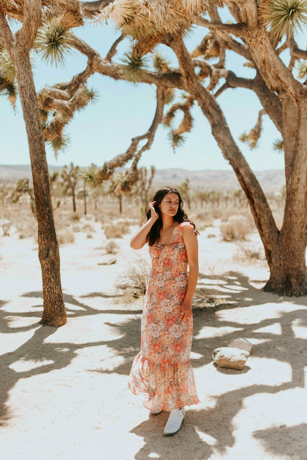 woman in white and red floral sleeveless dress standing on white sand during daytime