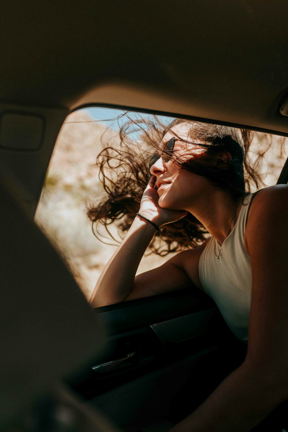 woman in white tank top sitting inside car during daytime