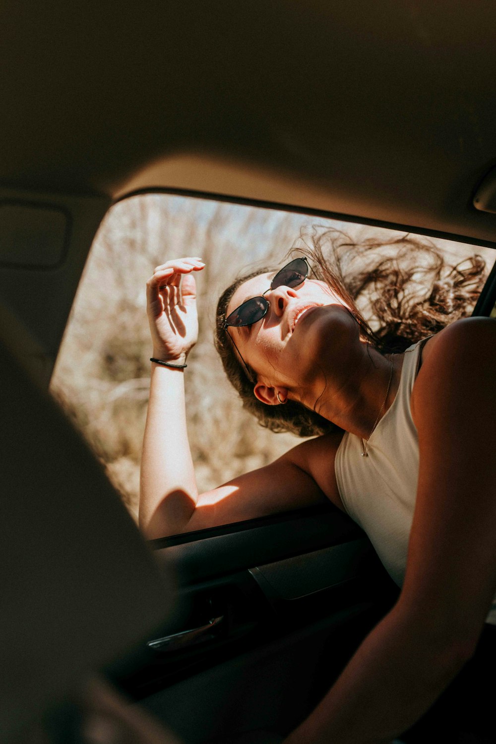 woman in white tank top wearing sunglasses sitting inside car