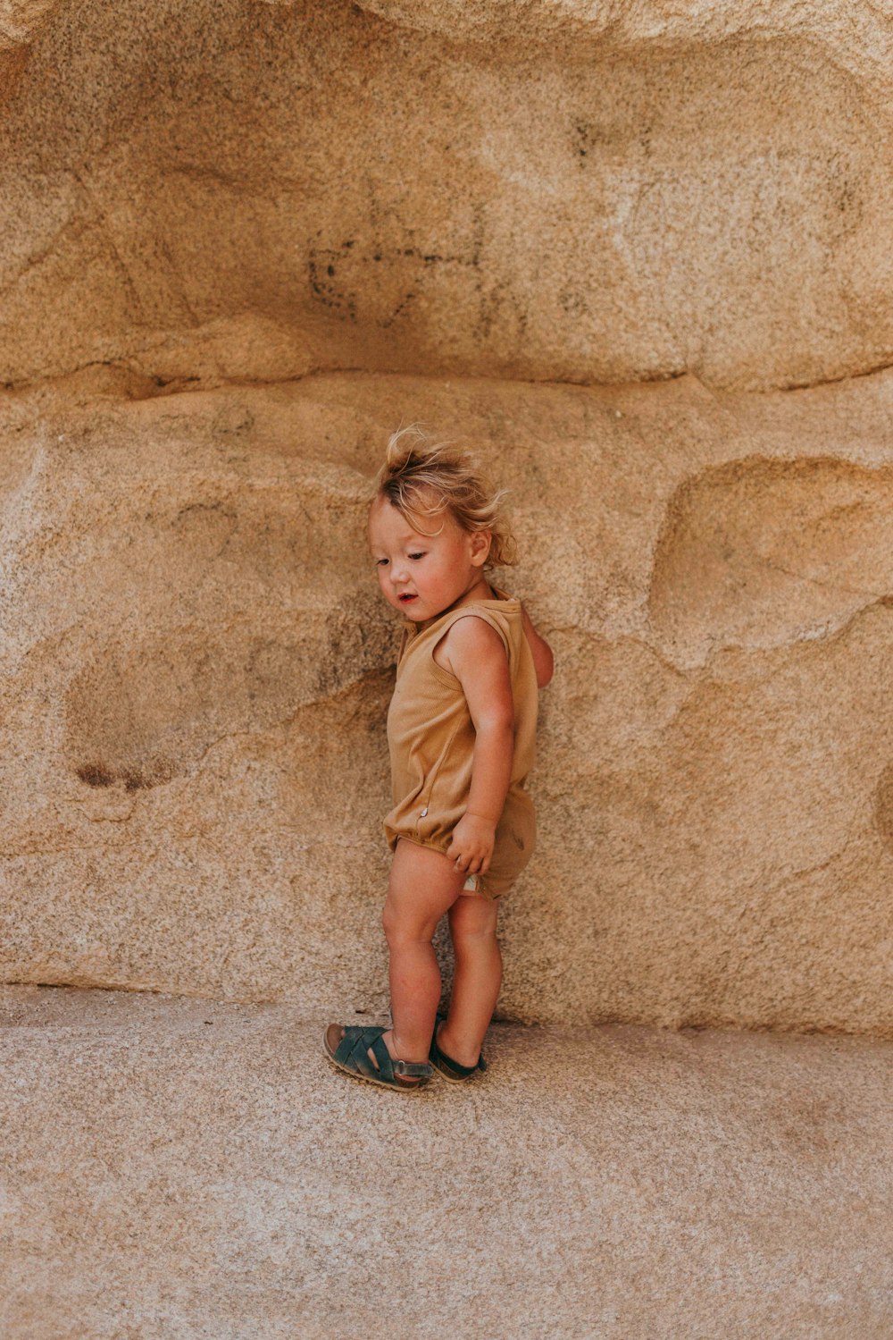 girl in brown sleeveless dress sitting on brown sand during daytime