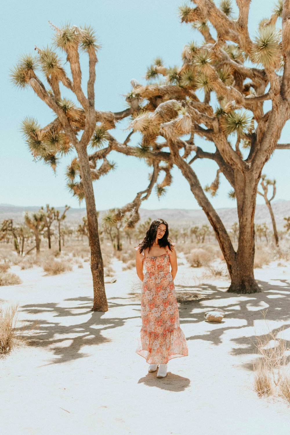woman in white and pink floral dress standing under brown tree during daytime