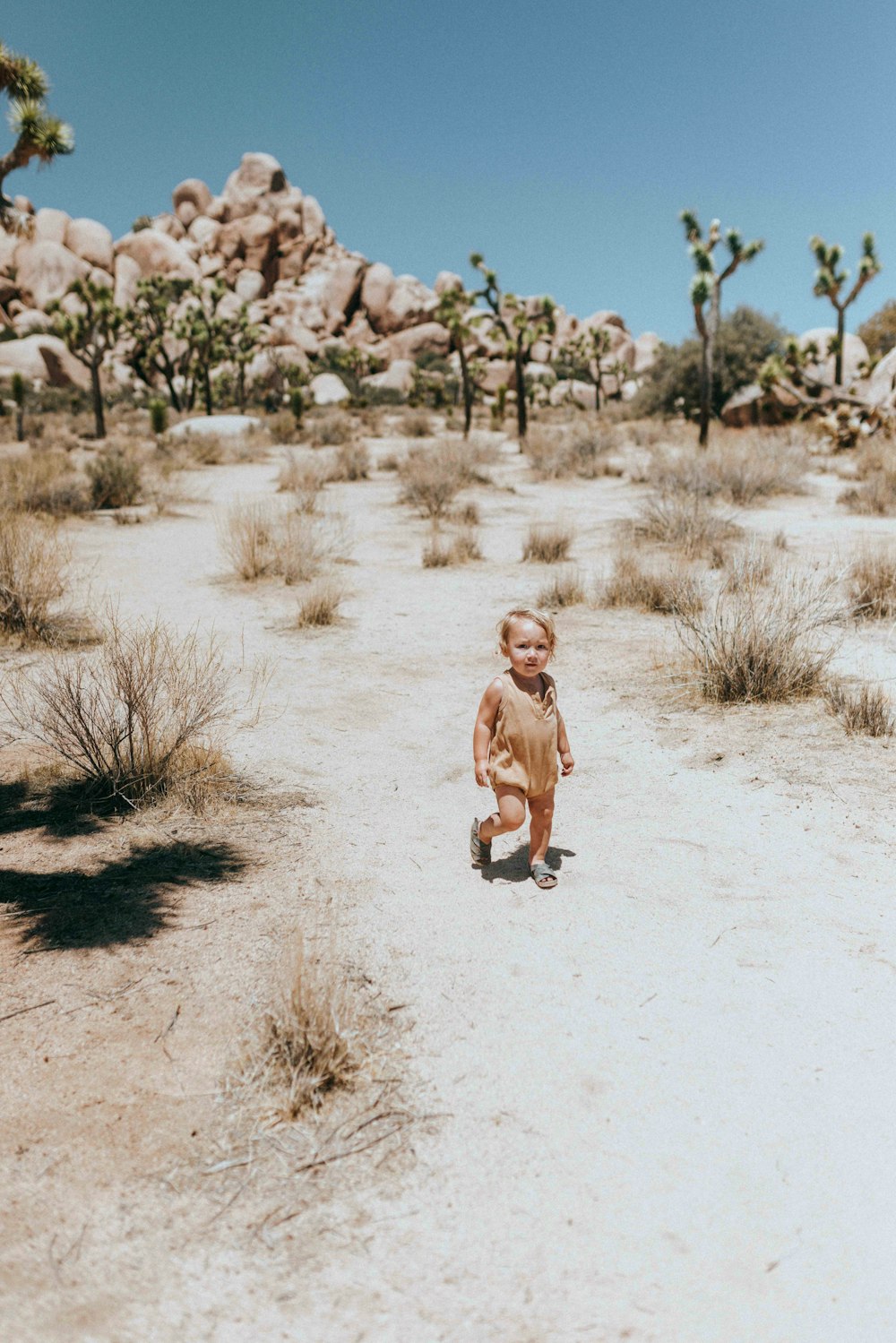 girl in brown dress running on white sand during daytime