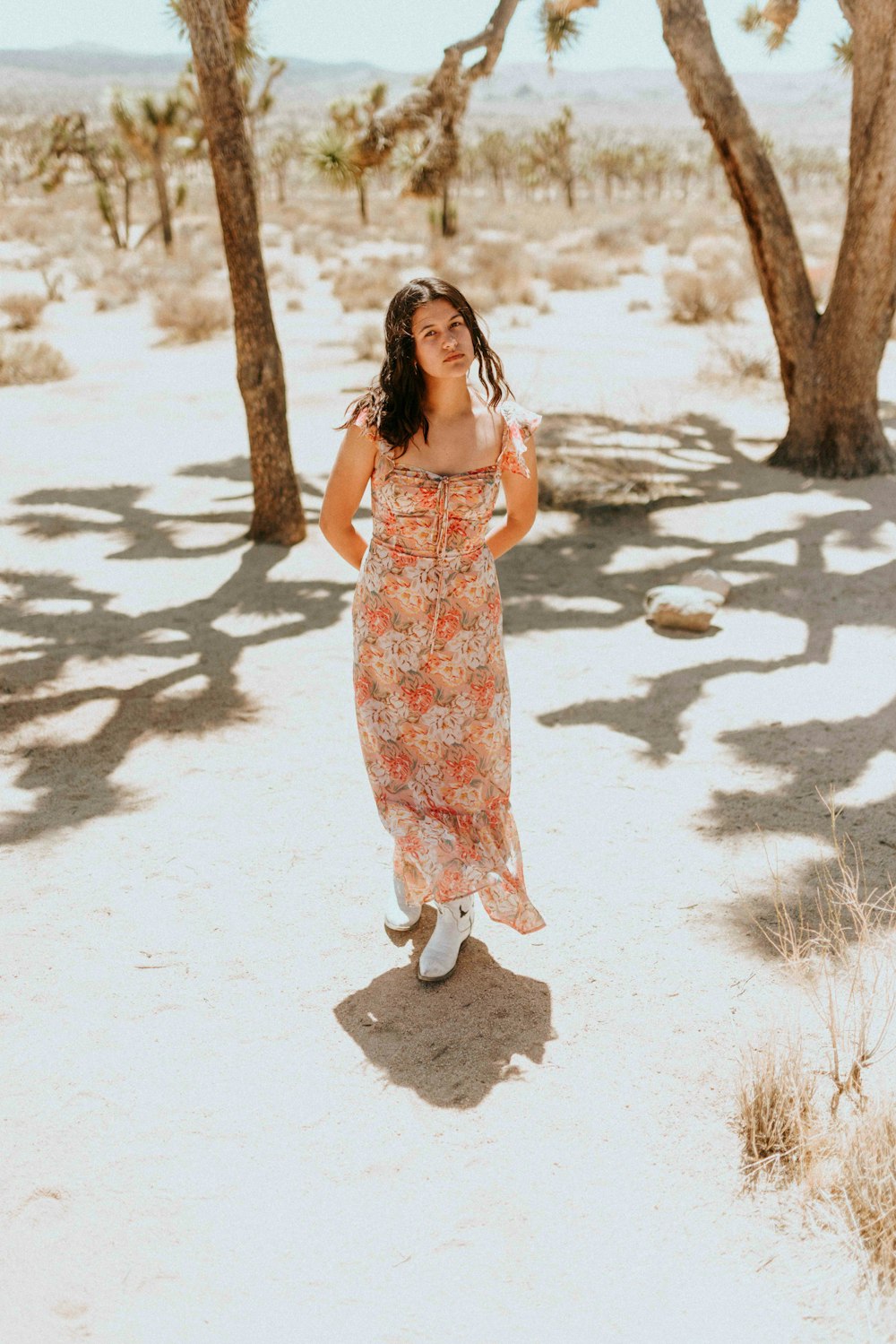 woman in red and white floral spaghetti strap dress standing on white sand during daytime