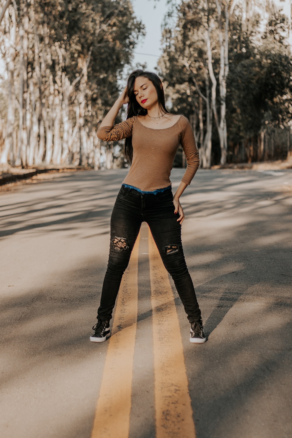 woman in brown tank top and black leggings standing on road during daytime