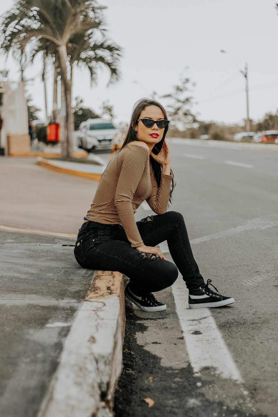 woman in brown sweater and black pants sitting on the road during daytime