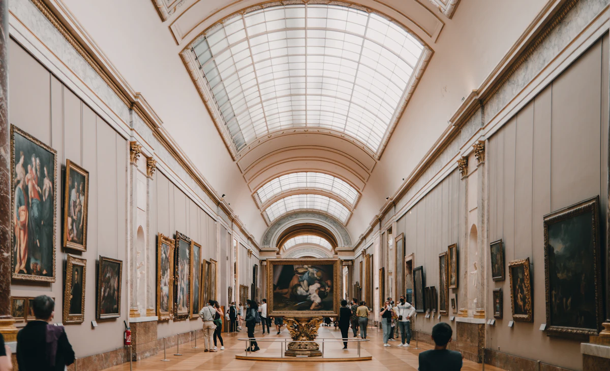 The interior of a small Paris art museum with paintings on the wall and visitors viewing them