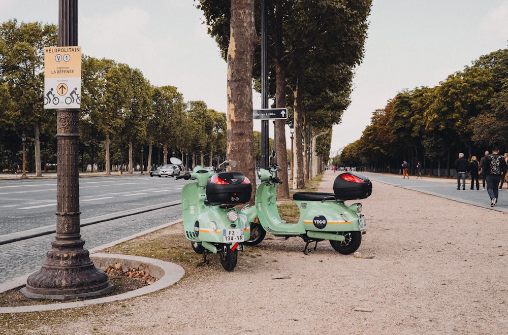 green motor scooter parked on side of road during daytime