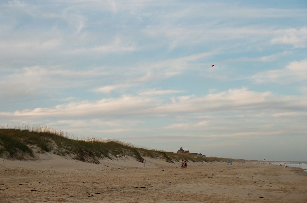 Menschen, die tagsüber auf braunem Sand unter weißen Wolken spazieren gehen