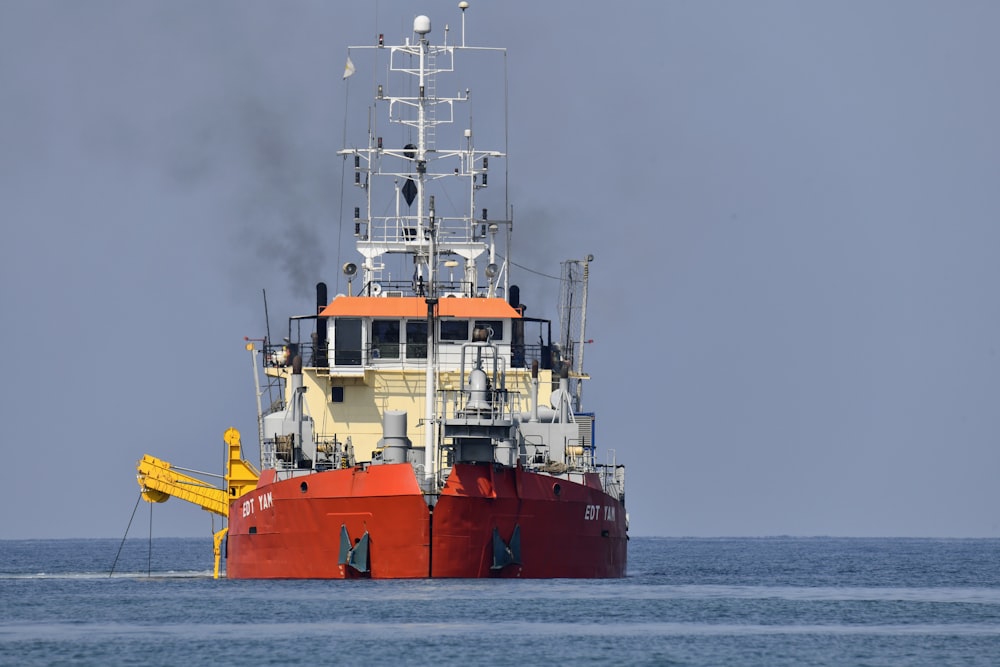 red and white ship on sea under gray sky