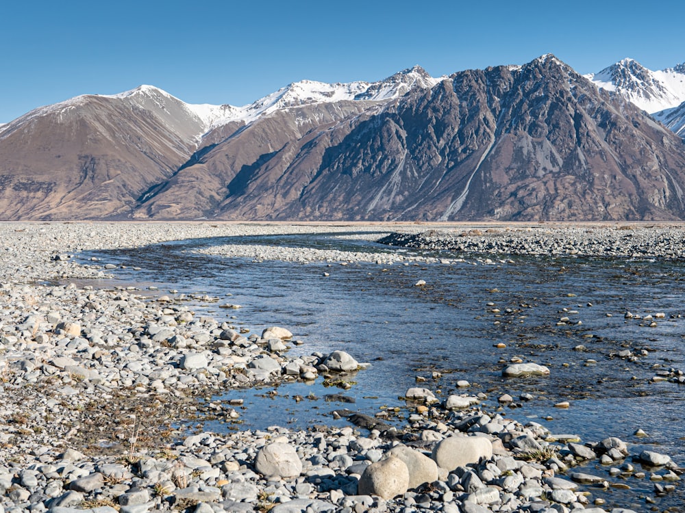 rocky river near mountains under blue sky during daytime