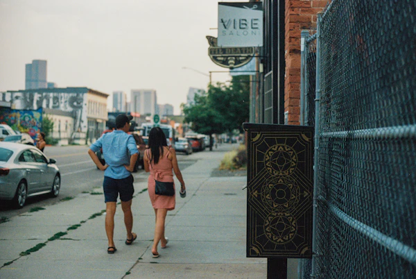 Woman in blue denim jacket walking on sidewalk during daytime