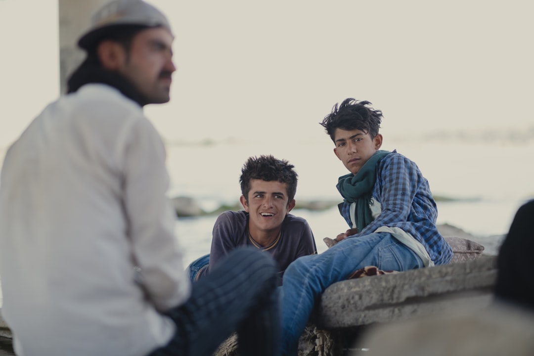 man in white long sleeve shirt sitting beside boy in blue and white plaid dress shirt