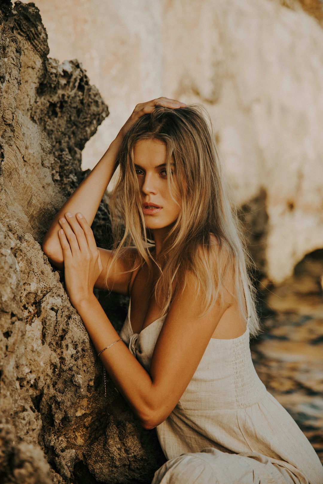 woman in white tank top leaning on brown rock
