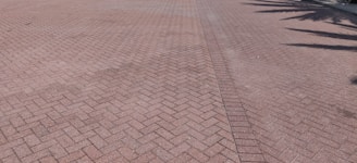A wide driveway paved with durable, interlocking bricks in a classic basketweave design.