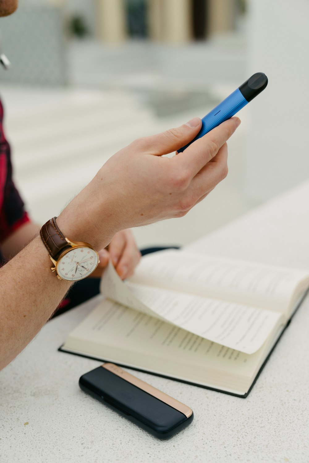 person wearing gold round analog watch with brown leather strap