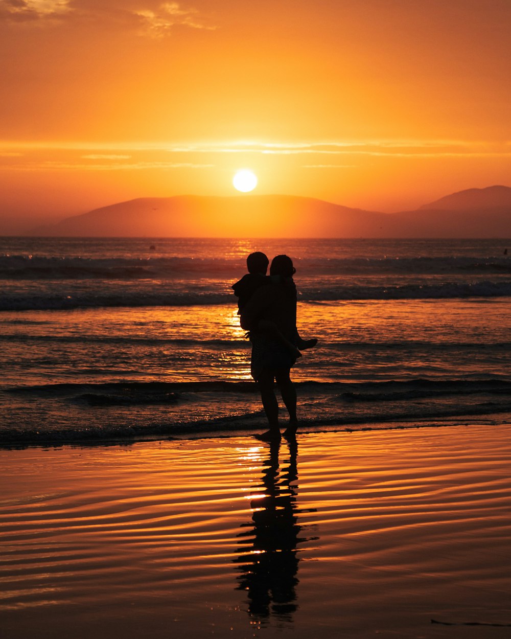 silhouette of man and woman kissing on beach during sunset