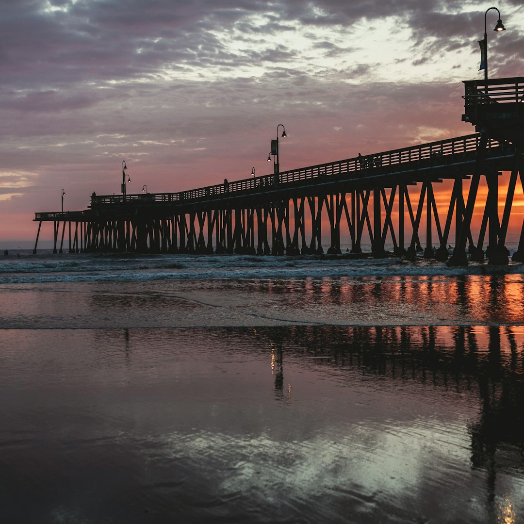 silhouette of dock on sea under cloudy sky during daytime