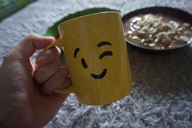 Happy customer holding a samoraes mug with a bright smile in a sunny kitchen.