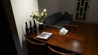 A cozy living room featuring a chenille loveseat, an oval mahogany dining table, and a white bookcase.