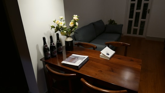 A cozy living room featuring a chenille loveseat, an oval mahogany dining table, and a white bookcase.