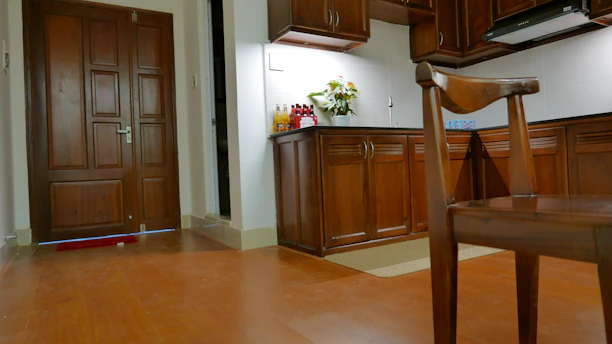 A warm, handcrafted wooden kitchen with custom cabinets and a matching staircase in the background.