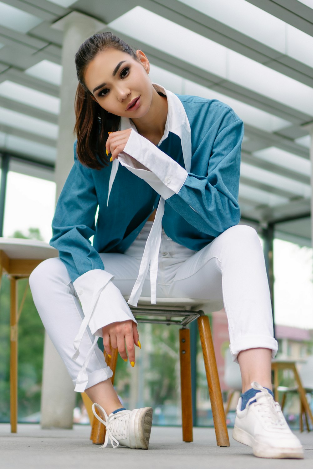 mulher no uniforme escolar azul e branco sentado na cadeira de madeira marrom