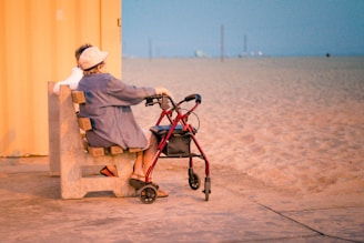 woman in gray dress shirt and white hat sitting on brown wooden bench near body of on on on on