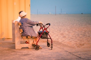 woman in gray dress shirt and white hat sitting on brown wooden bench near body of on on on on