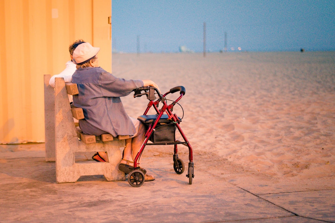 woman in gray dress shirt and white hat sitting on brown wooden bench near body of on on on on