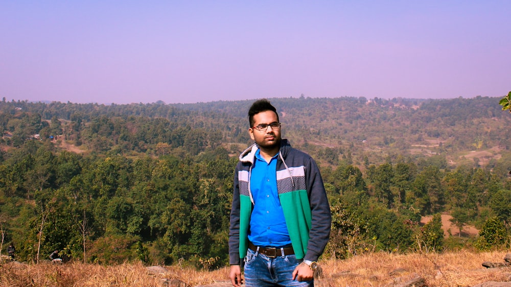 man in green jacket standing on brown grass field during daytime