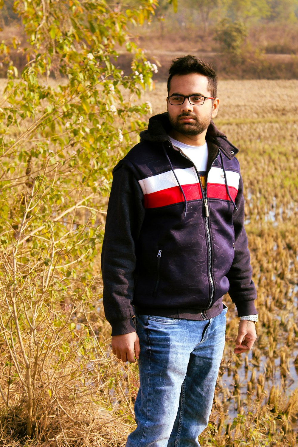man in black and red zip up jacket standing on brown grass field during daytime