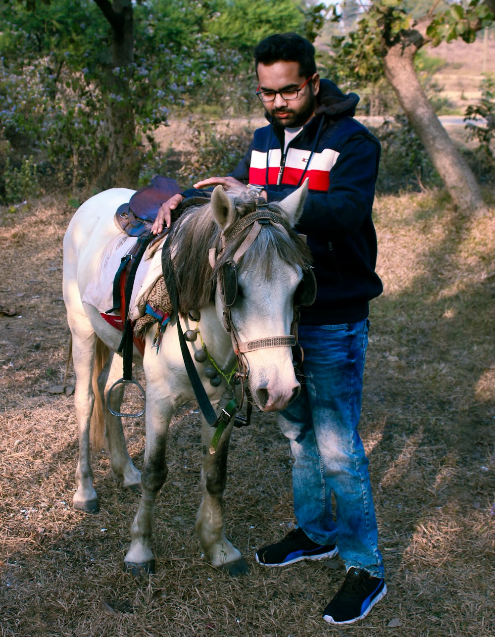 woman in blue denim jeans and red jacket riding white horse during daytime