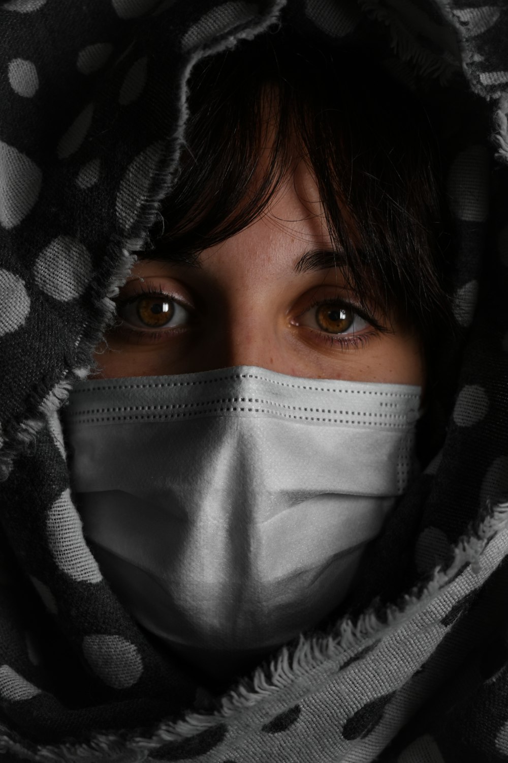 Frau bedeckt ihr Gesicht mit schwarz-weißem Textil