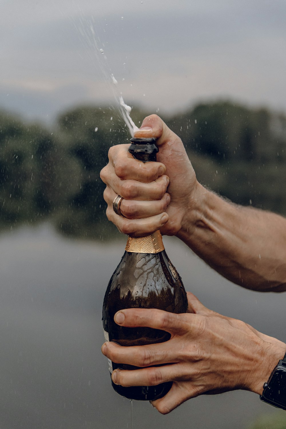 person holding bottle pouring water on body of water