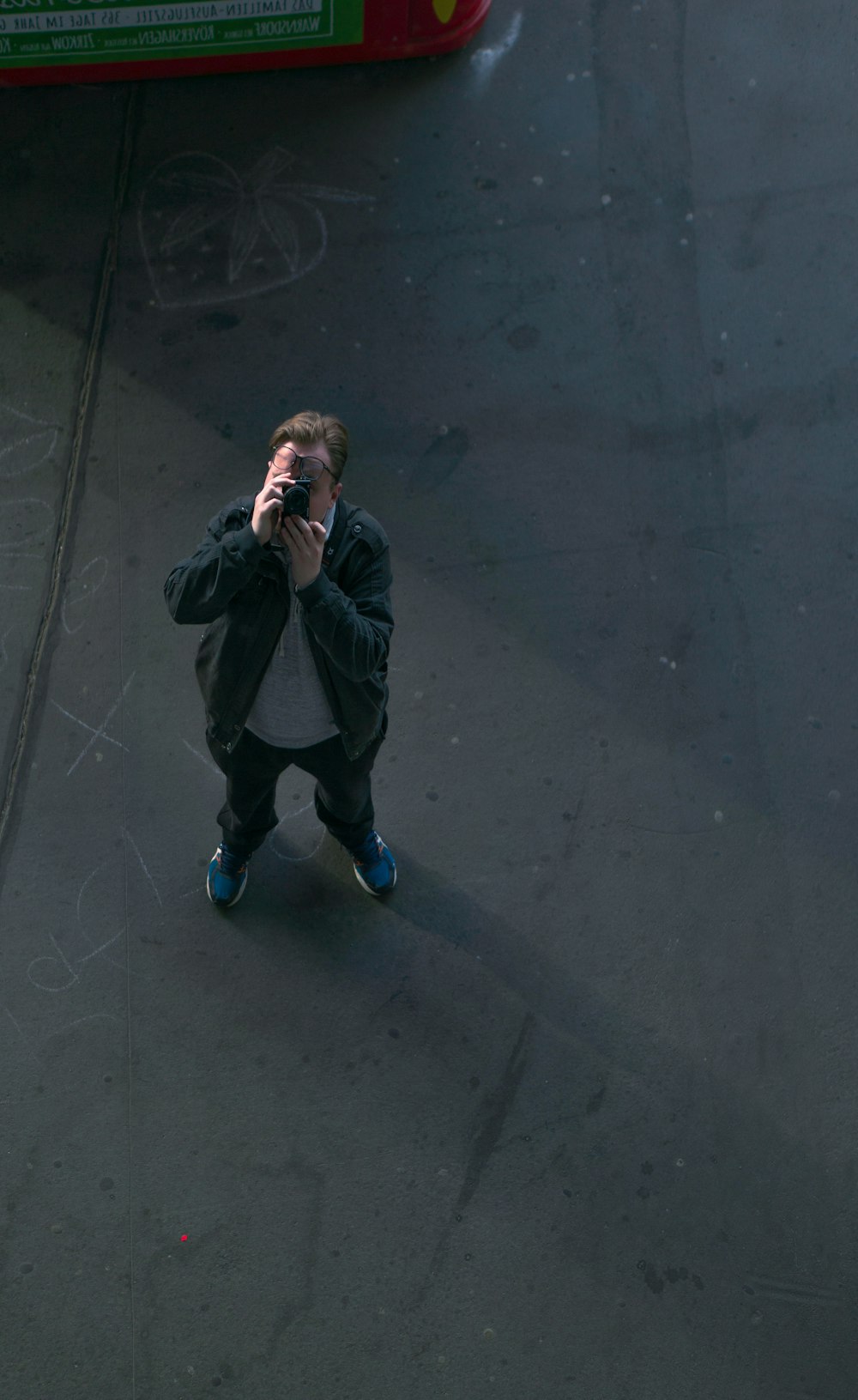 man in black jacket and blue pants sitting on black concrete floor
