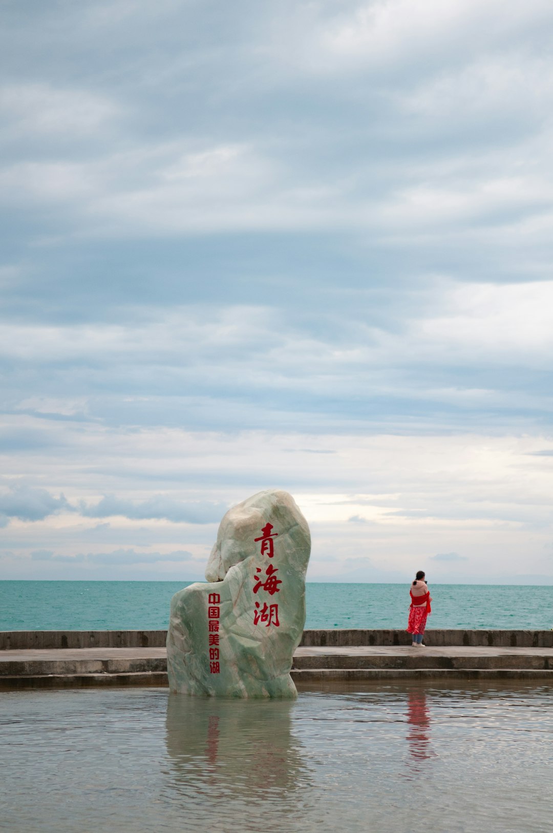 woman in pink shirt standing on brown wooden dock during daytime