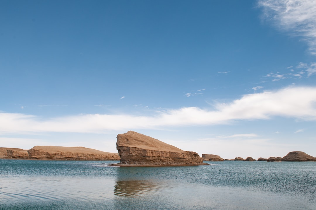 brown rock formation on body of water under blue sky during daytime