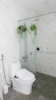 Bathroom with clean white tiles, a shower cabin, and fresh towels.