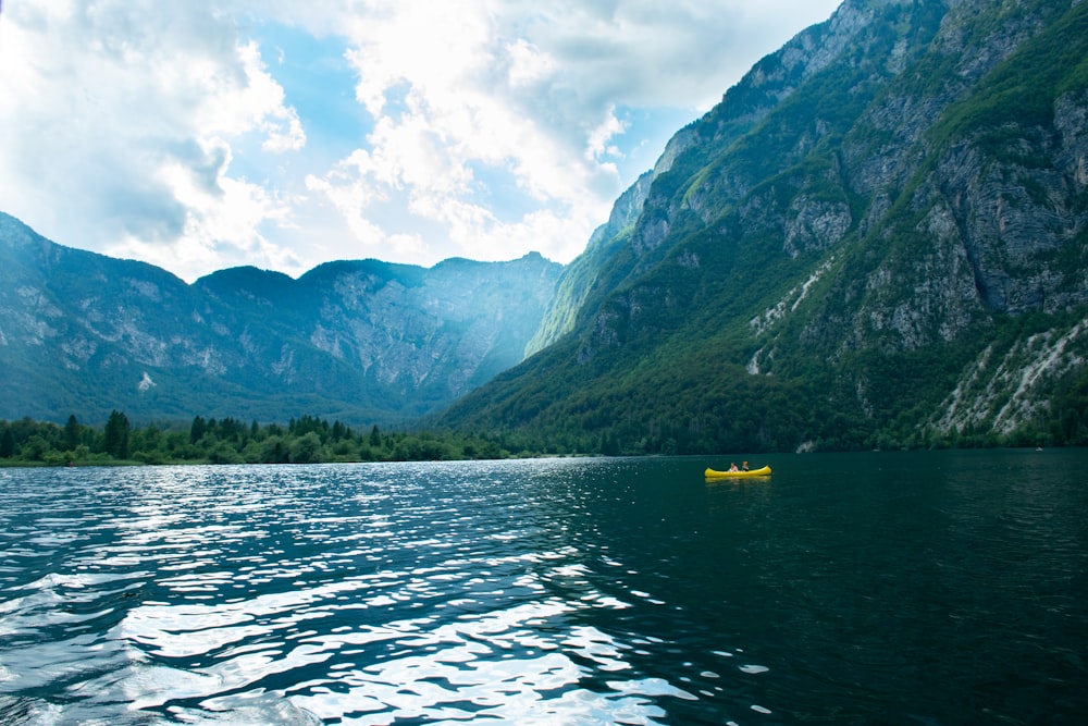 green mountains beside body of water under blue and white sunny cloudy sky during daytime