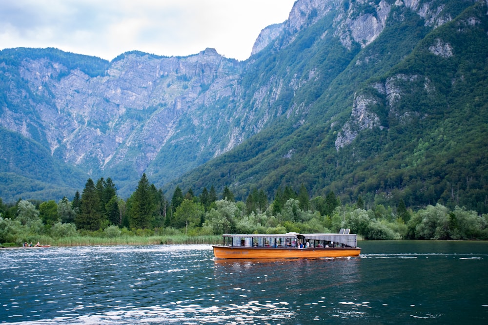 brown boat on water near green mountain during daytime