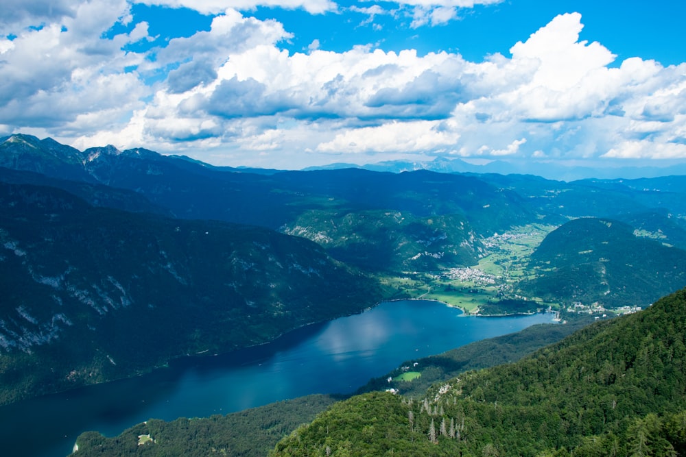 green mountains near lake under white clouds and blue sky during daytime