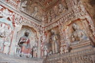 Detailed carvings on a temple wall depicting scenes from monastic life in the Mulasarvastivada tradition.