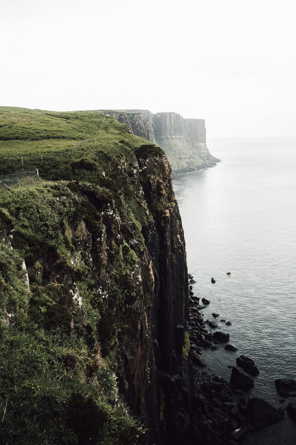 green and brown rock formation beside body of water during daytime