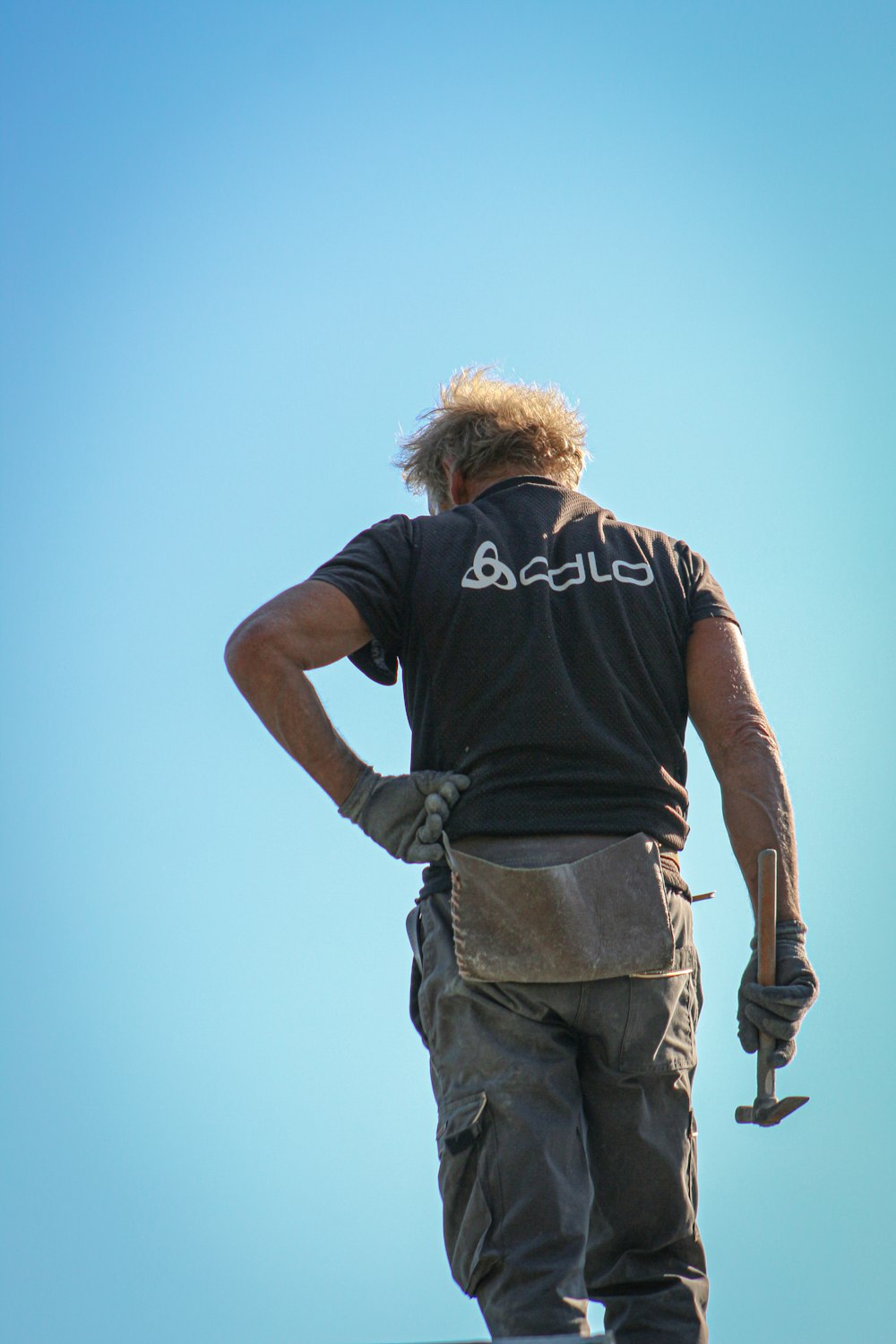 man in black t-shirt and gray cargo pants standing under blue sky during daytime