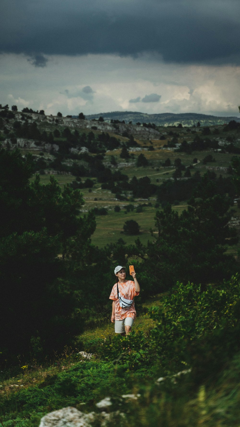 man in white t-shirt and brown shorts standing on green grass field during daytime